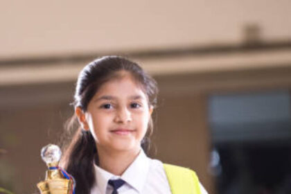 Little girl holding trophy at school campus