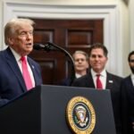 President Trump speaks at a White House podium as Michael Dell and Susan Dell stand behind him during the Trump Accounts announcement