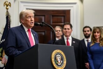President Trump speaks at a White House podium as Michael Dell and Susan Dell stand behind him during the Trump Accounts announcement