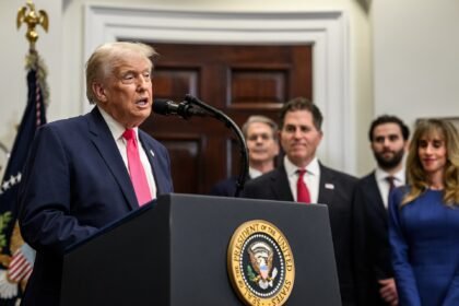 President Trump speaks at a White House podium as Michael Dell and Susan Dell stand behind him during the Trump Accounts announcement