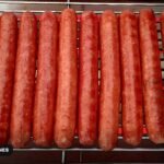 Hot dogs lined up on a grill rack