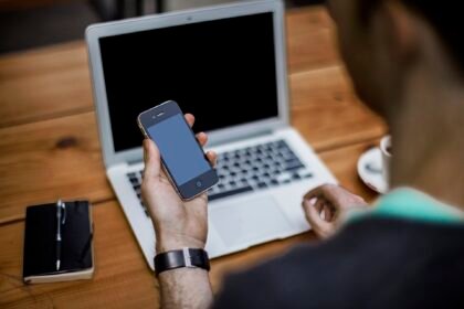 A man holding a smartphone at his desk