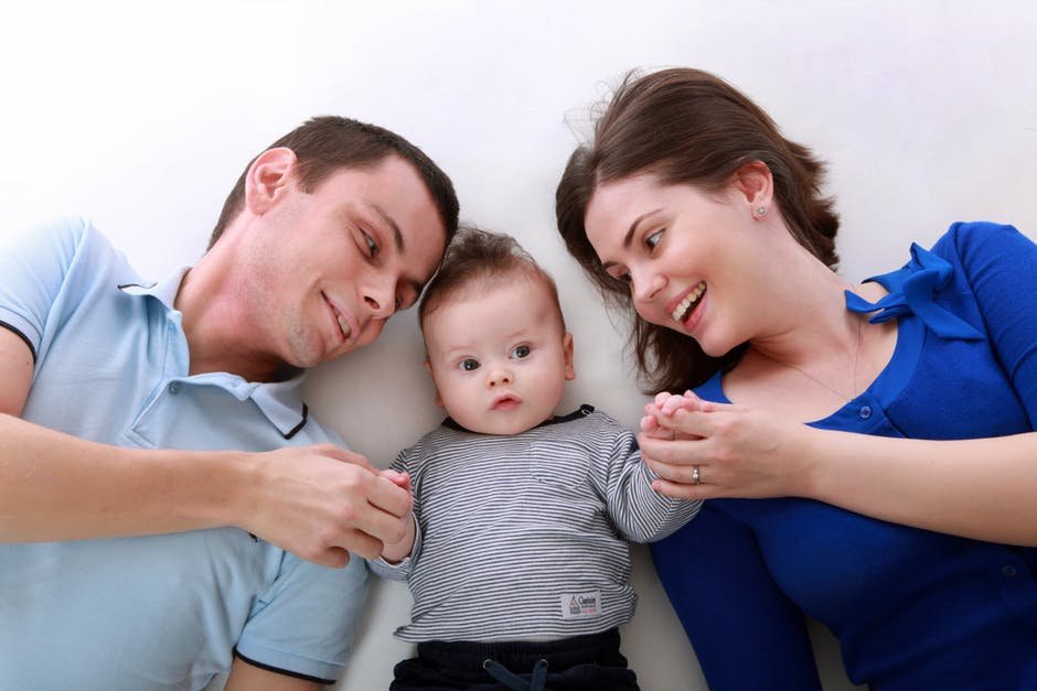 Smiling parents lying next to their baby, illustrating the $1,000 Trump Account deposit for children born 2025 to 2028
