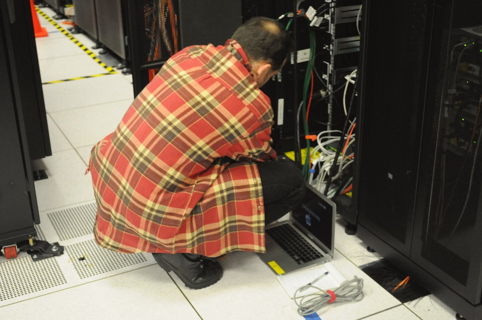 A technician with a laptop working on a server rack