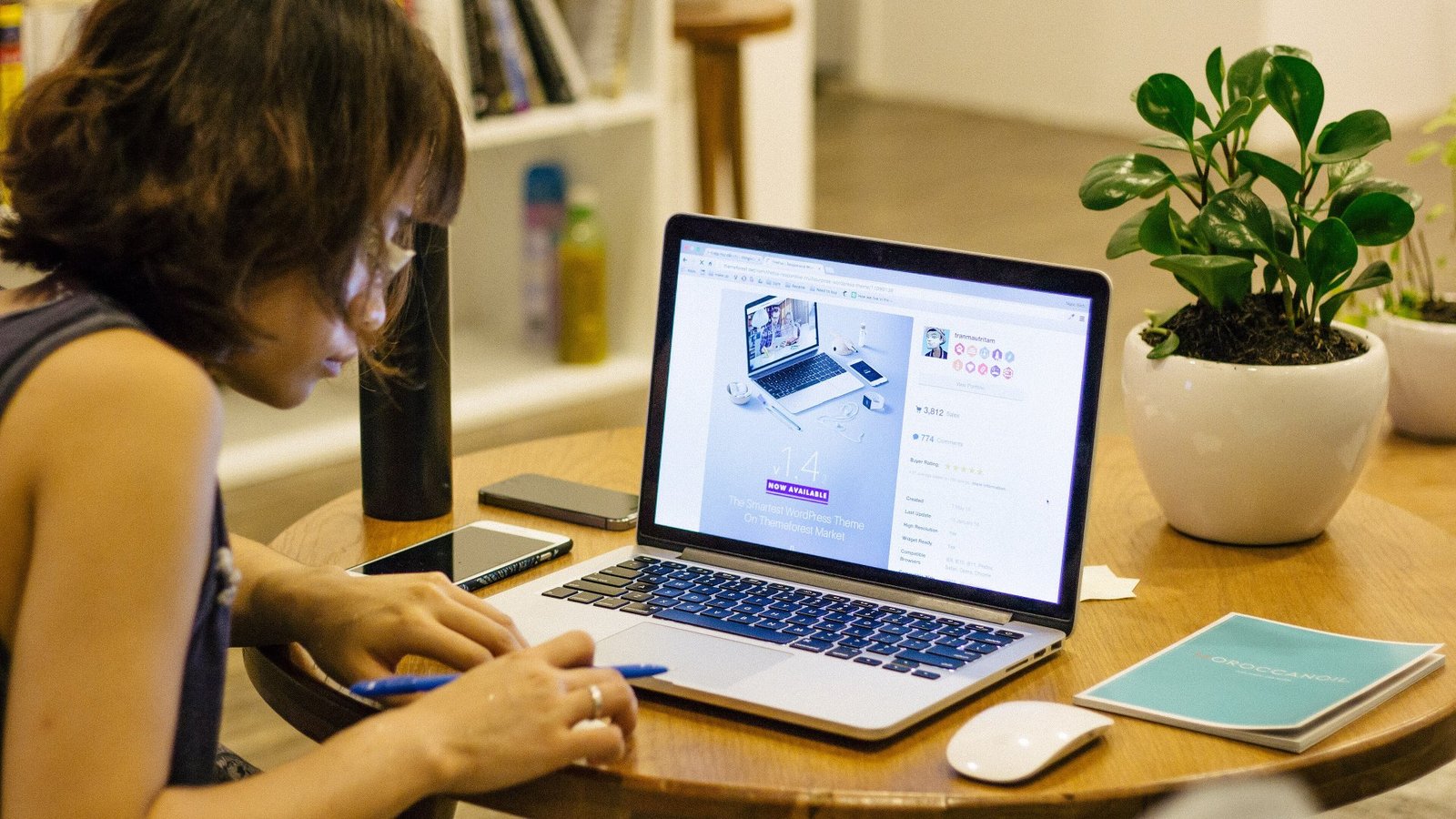 A person taking notes at a coffee table with a laptop